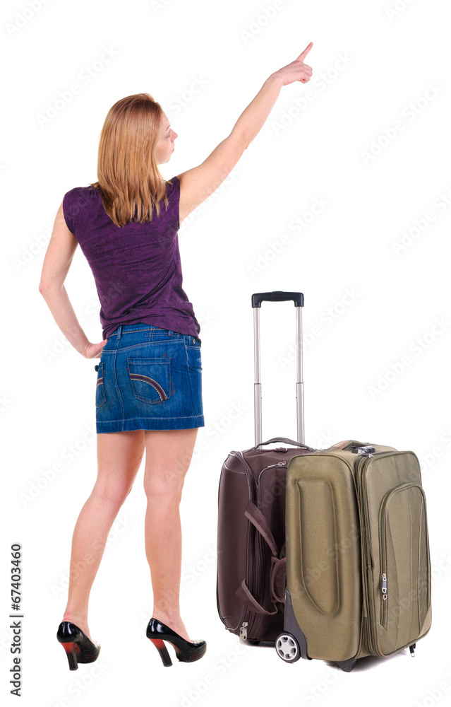 Beautiful young woman in dress traveling with suitcas and point Beautiful young woman in dress traveling with suitcas and point