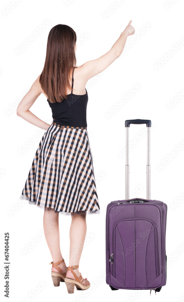 Back view of young brunette woman traveling with suitcas and poi Back view of young brunette woman traveling with suitcas and poi