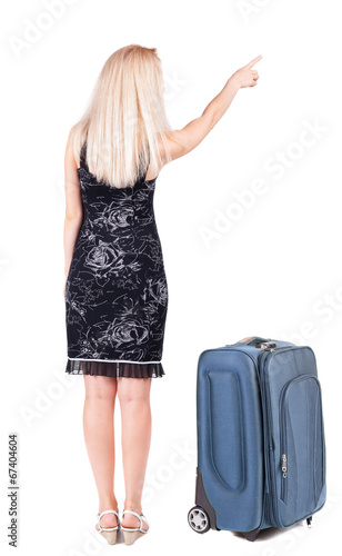 Back view of young brunette woman traveling with suitcas and poi