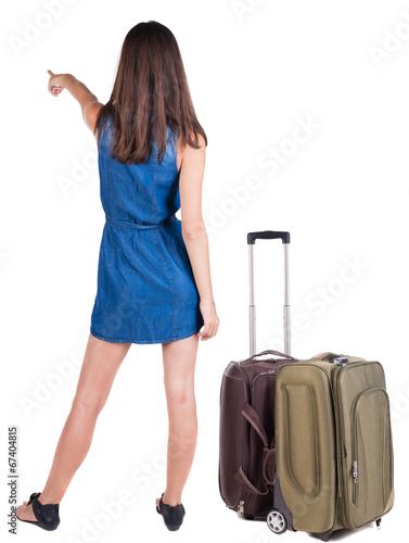 Back view of young brunette woman traveling with suitcas and poi