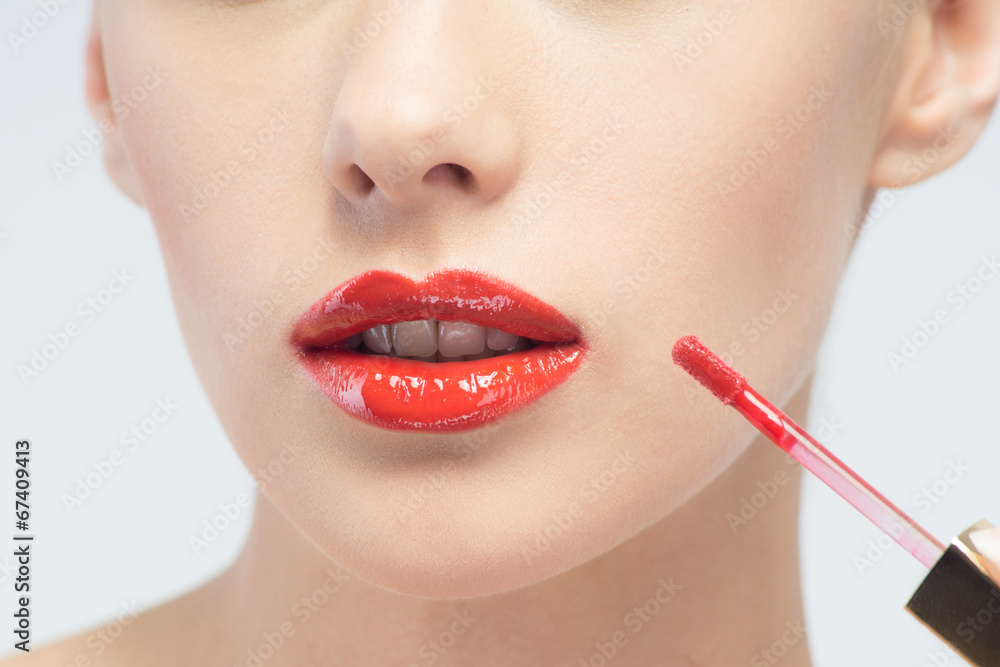 Beautiful woman applying lip gloss Beautiful woman applying lip gloss
