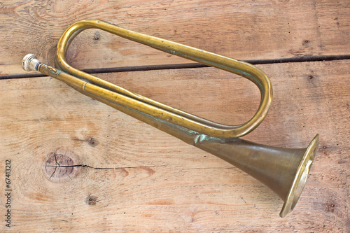 Old broken army trumpet on wooden background
