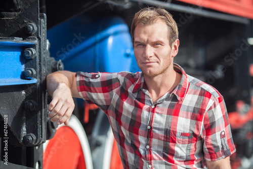 Portrait of man in a checkered shirt near the old locomotive