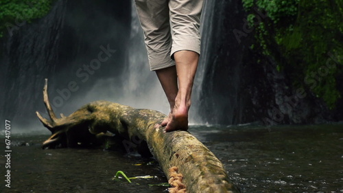 Man walking on wood log by waterfall, super slow motion, 240fps