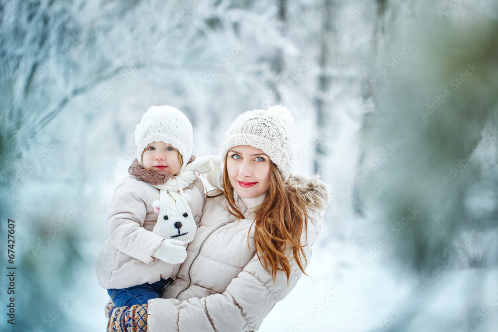 Mother holds daughter on hands in winter forest