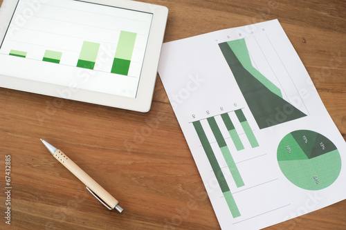 Fotografie Tablet with graphs and charts on wooden table