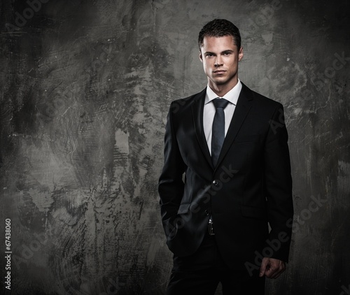 Well-dressed man in black suit against grunge wall