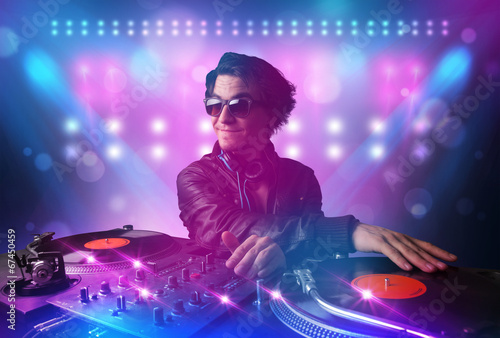 Disc jockey mixing music on turntables on stage with lights and © ra2 studio