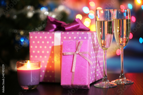 Many gifts and glass of champagne on bright background
