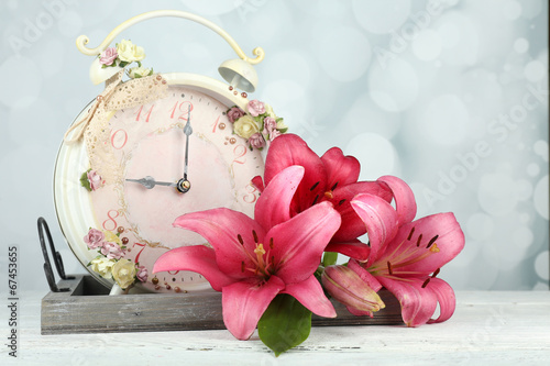 Fototapeta Naklejka Na Ścianę i Meble -  Beautiful lily with clock on wooden tray on bright background