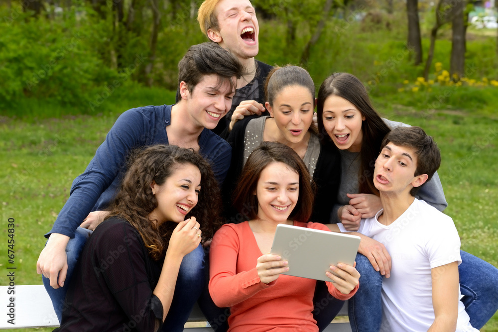 Group of young adults browsing a tablet outside Group of young adults browsing a tablet outside