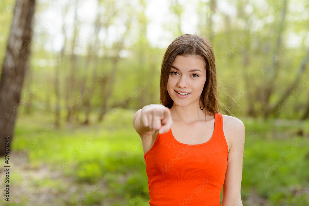 beautiful young woman in park points with a finger forward beautiful young woman in park points with a finger forward