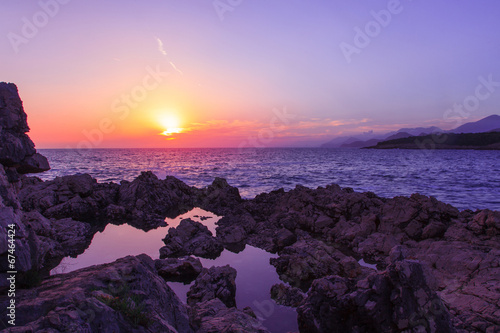 Horizontal photo of sunset on rocky beach photo