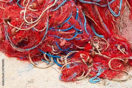 Heap of red fishing net and ropes on the quay.