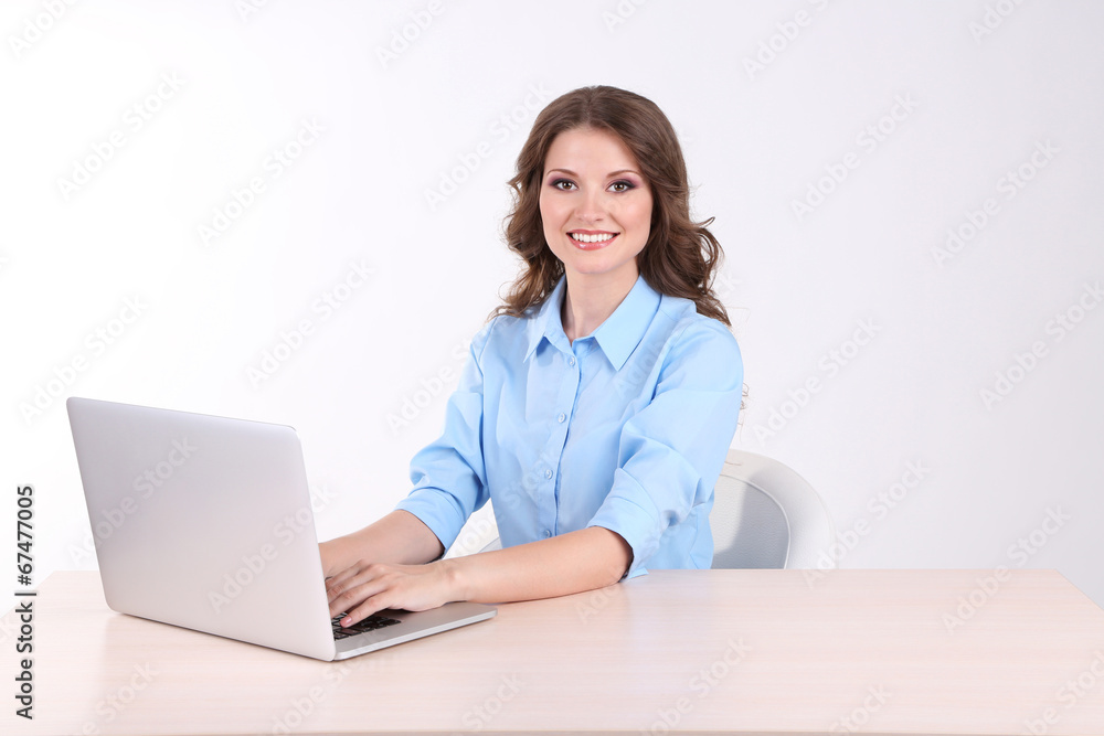 Young business woman sitting at table with notebook in room Young business woman sitting at table with notebook in room