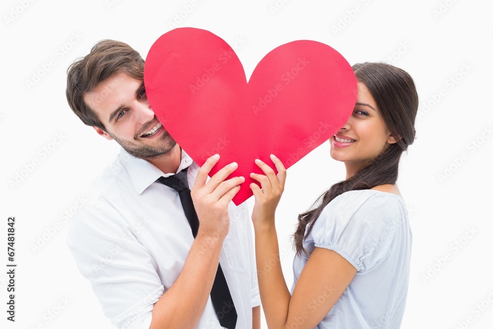 Couple smiling at camera holding a heart