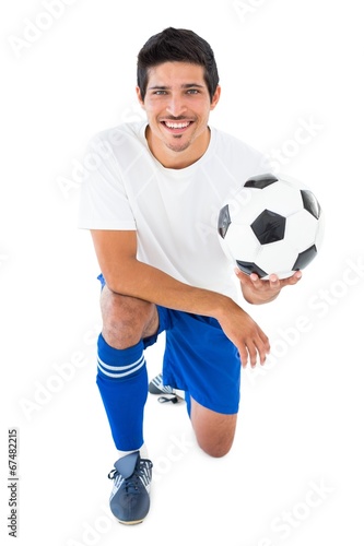 Football player in blue kneeling with ball © WavebreakMediaMicro