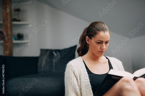 Young woman reading a book at home
