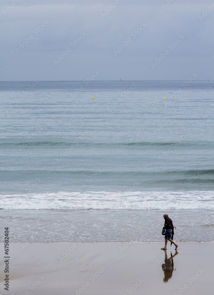 Anciano con paraguas paseando por la playa