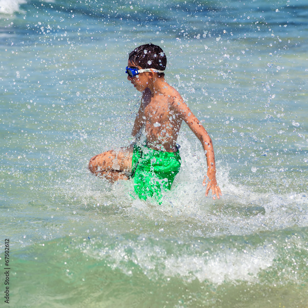 child splash jumping into the sea on the beach