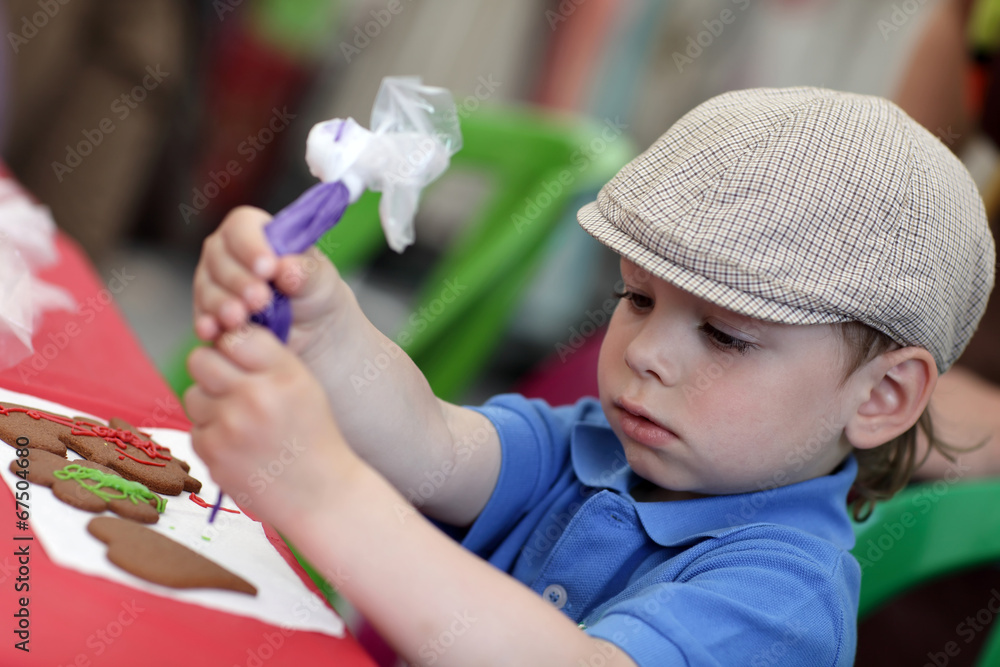Obraz premium Boy decorating gingerbread shapes
