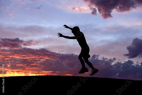 Boy jumps at sunset.