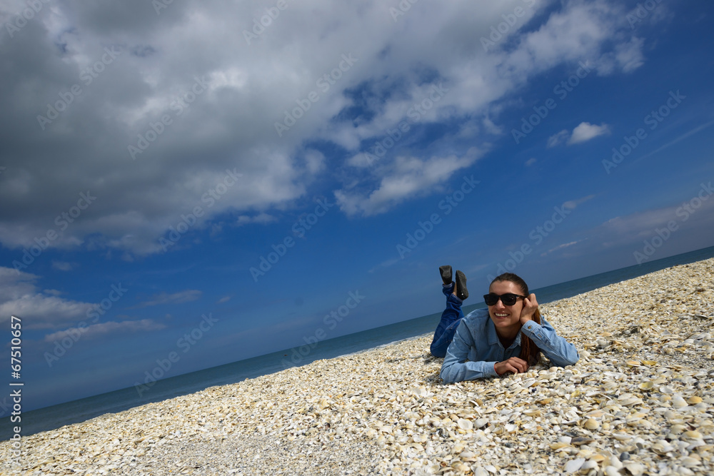 Young woman lying on a beach against blue sky on a summer day Young woman lying on a beach against blue sky on a summer day