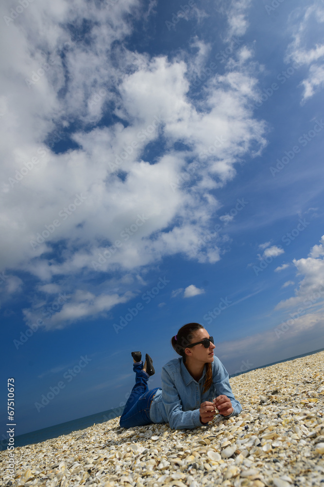 Young woman lying on a beach against blue sky on a summer day Young woman lying on a beach against blue sky on a summer day