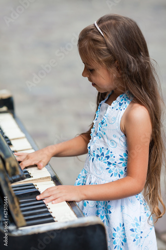 Little girl playing on a piano