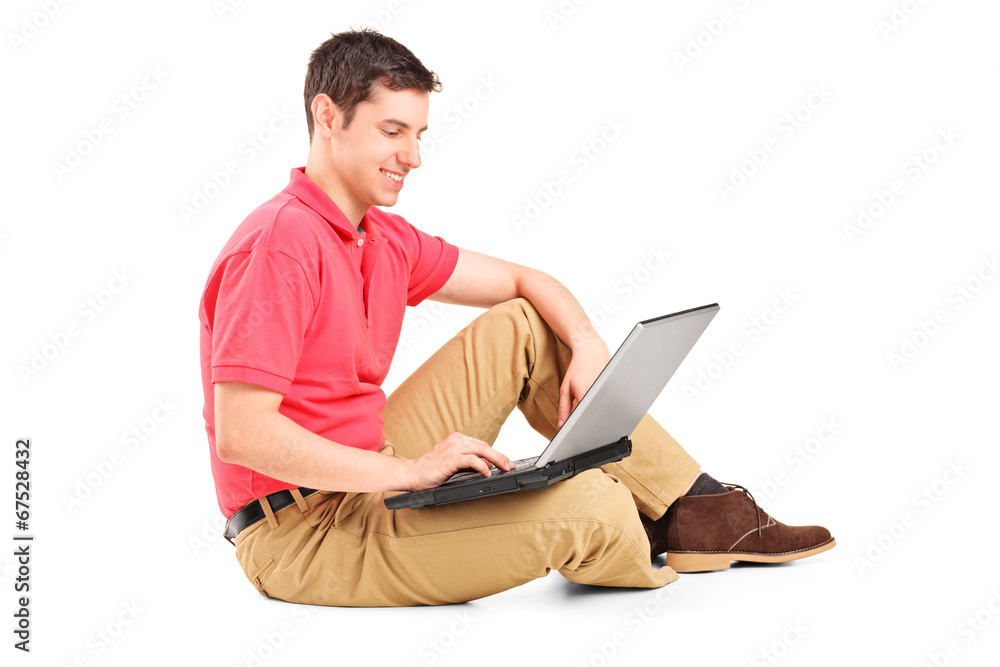 Young man working on laptop seated on the floor Young man working on laptop seated on the floor