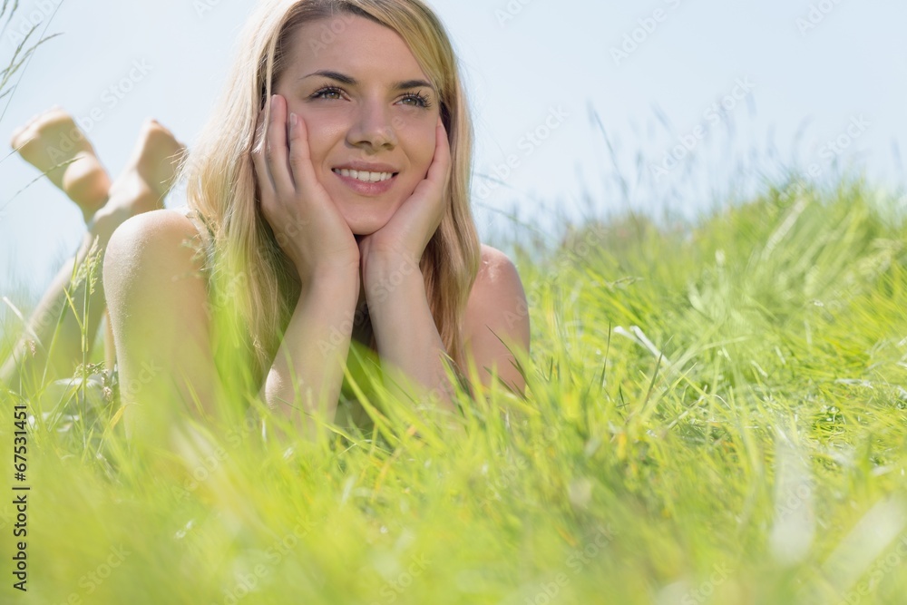 Pretty blonde in sundress lying on grass smiling