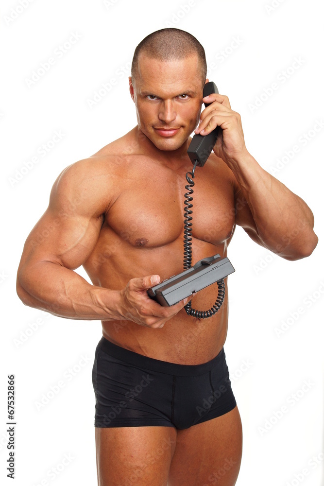 Fototapeta premium Muscular man speaks into telephone on isolated background
