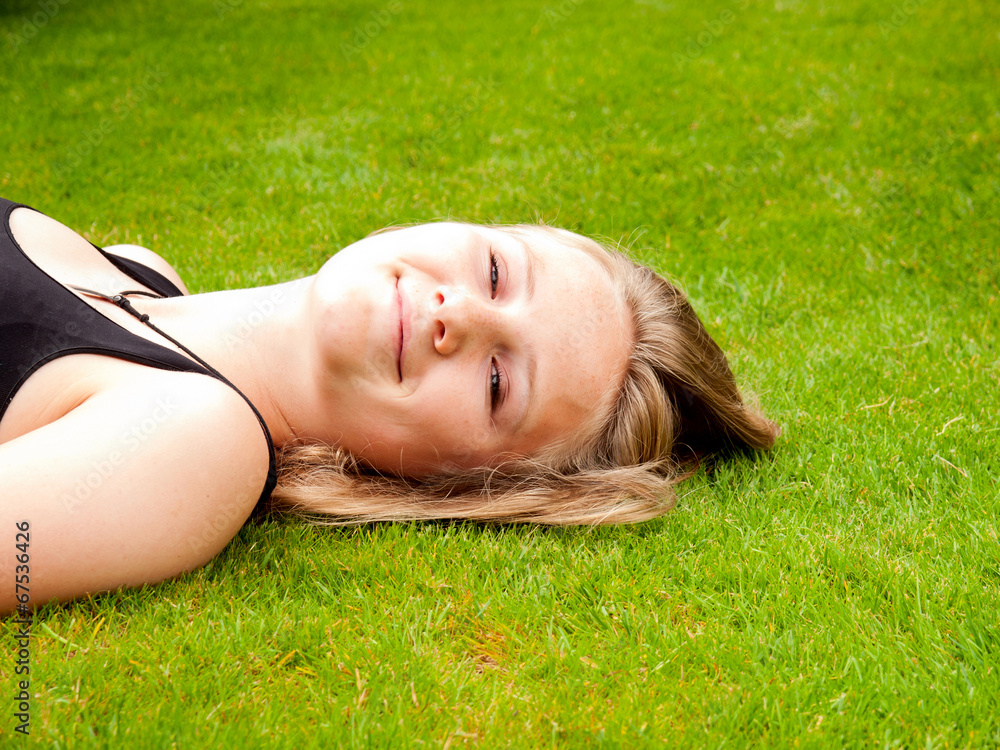 Beautiful smiling teenage girl lying on her back in the grass Beautiful smiling teenage girl lying on her back in the grass