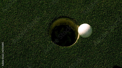 Golf ball rolling into the hole on putting green