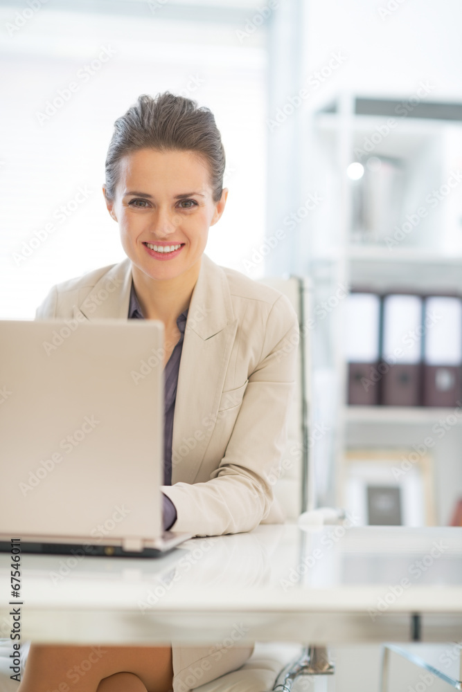 Happy business woman working on laptop in office Happy business woman working on laptop in office