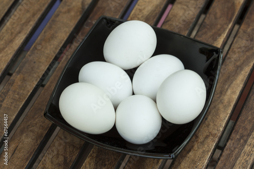 Eggs in a black bowl isoated on wooden table. photo