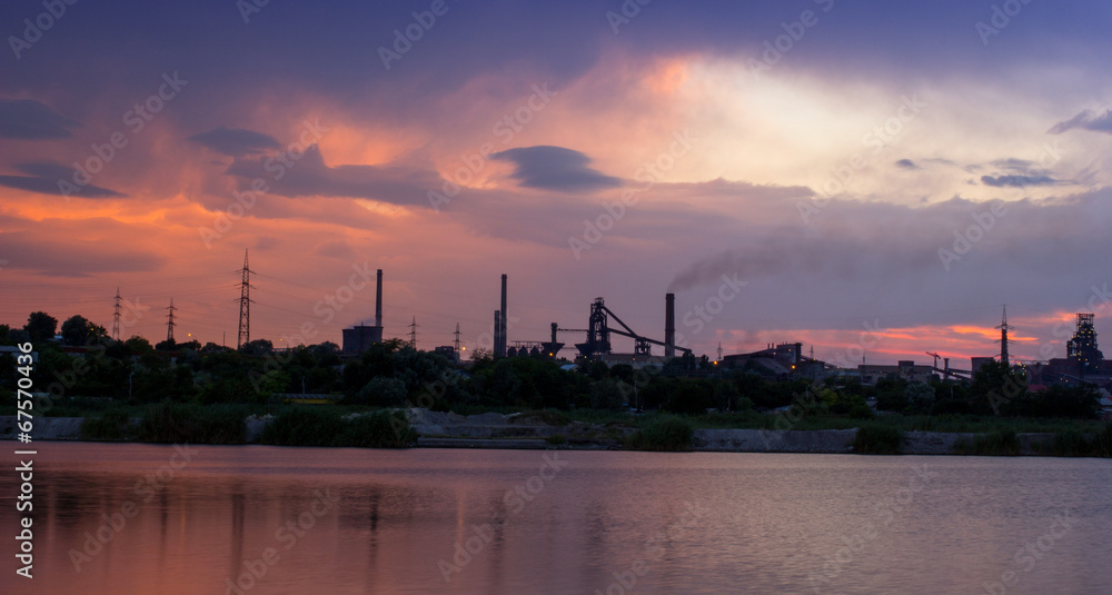 Silhouette of industrial factory at sunset mirror in water