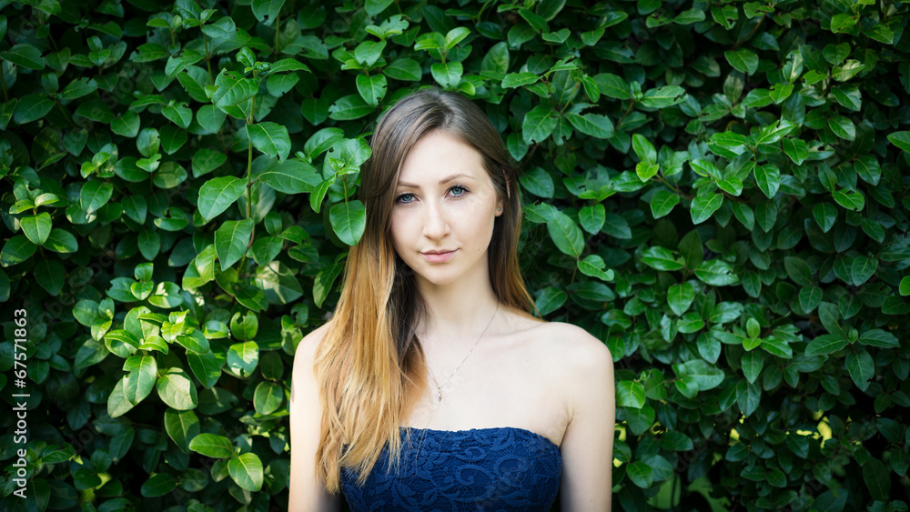 Close up portrait of young woman with natural hedge background Close up portrait of young woman with natural hedge background