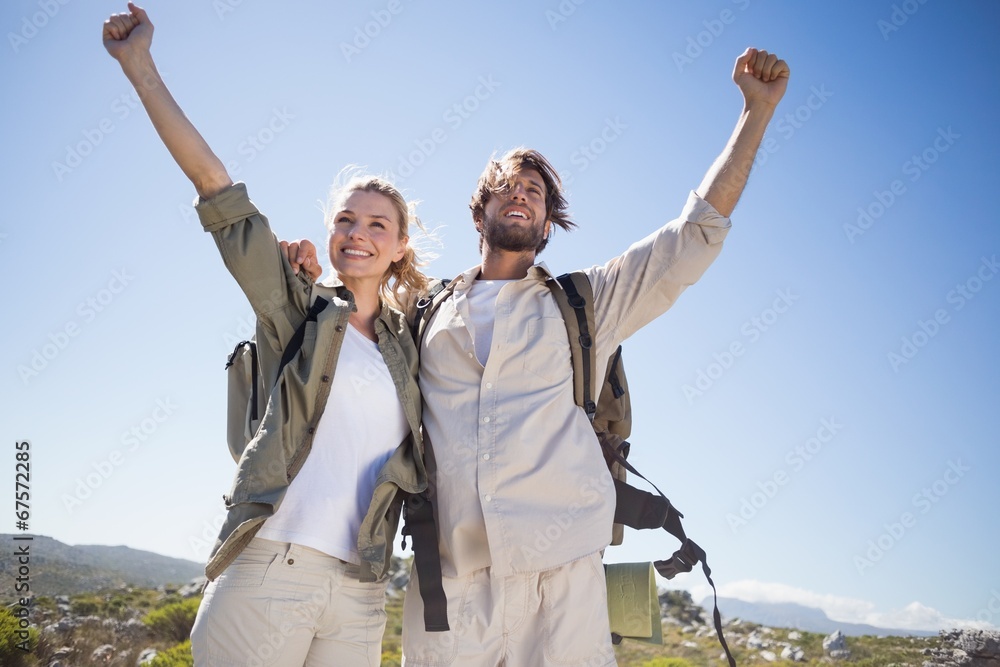 Hiking couple standing on mountain terrain cheering