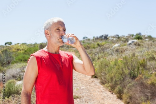 Fit man drinking water on mountain trail