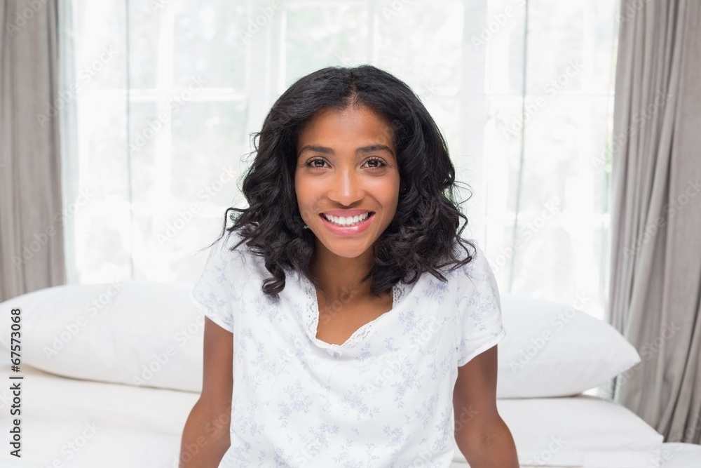 Pretty woman smiling at camera sitting on bed Pretty woman smiling at camera sitting on bed
