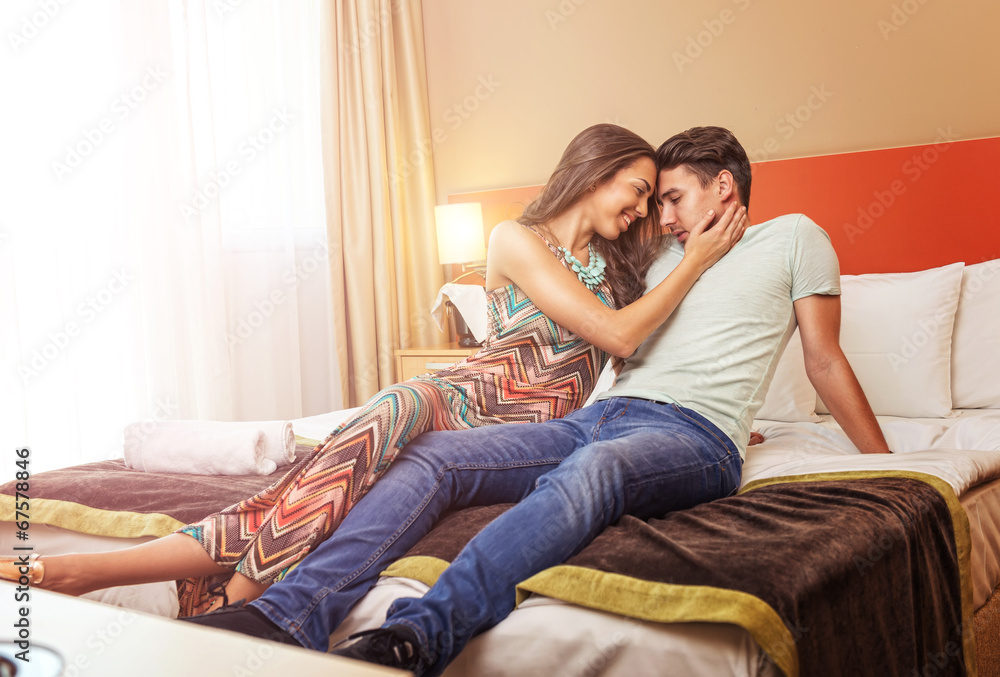 Young couple's arrival to the hotel, sitting on the bed Young couple's arrival to the hotel, sitting on the bed