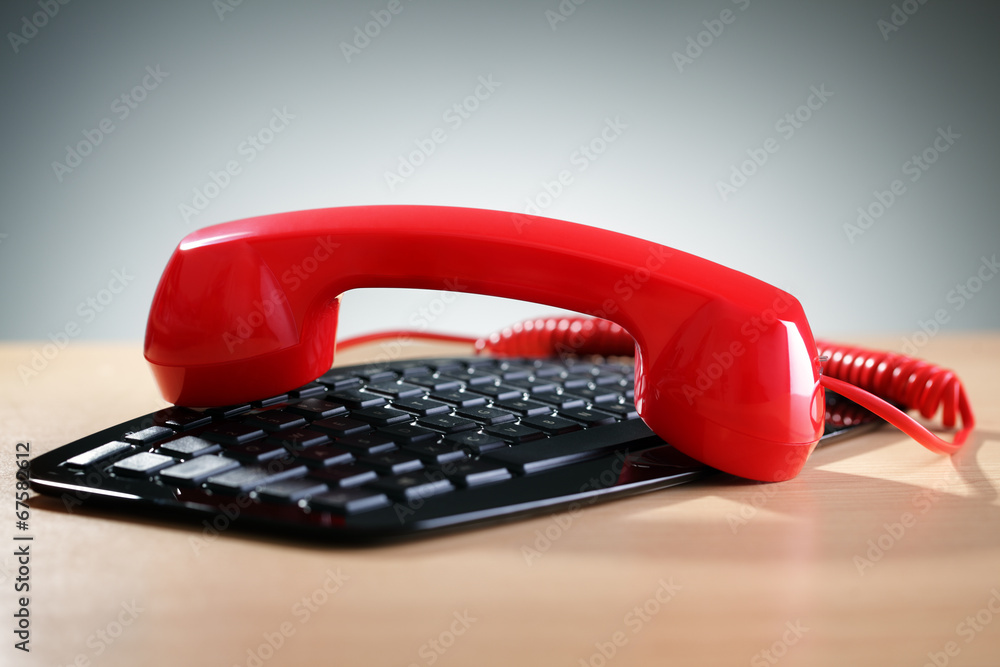 Red telephone receiver on keyboard Red telephone receiver on keyboard