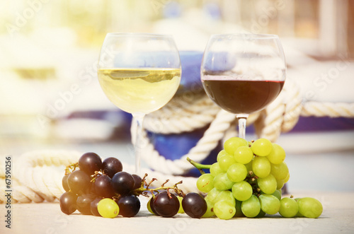 Pair of wineglasses and grapes against yachts in La Spezia, Ital