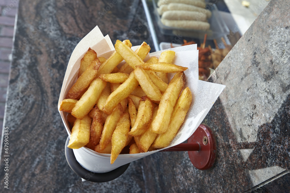 Potatoes fries in a little white paper bag hanging at the wall f Potatoes fries in a little white paper bag hanging at the wall f