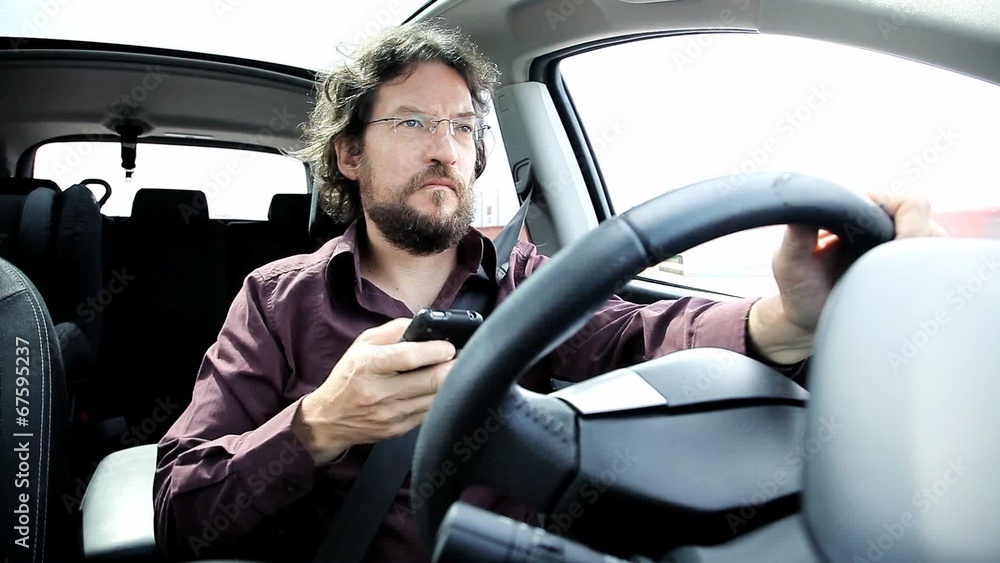 Man texting cell phone while driving car