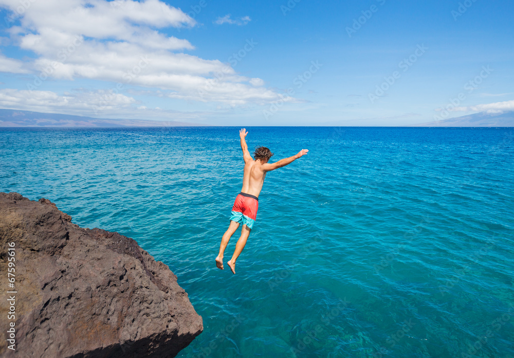 Man jumping off cliff into the ocean