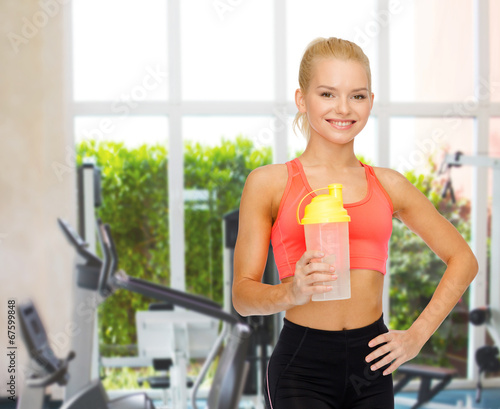smiling sporty woman with protein shake bottle