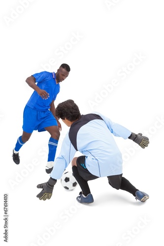 Football player in blue striking at keeper