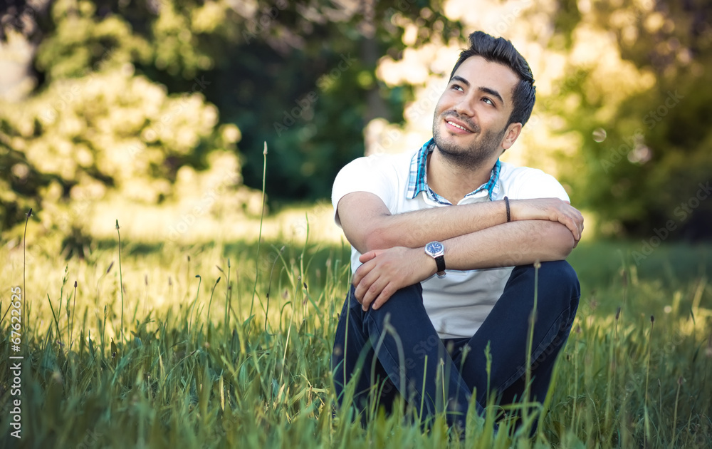 Fototapeta premium Happy young man sitting on meadow